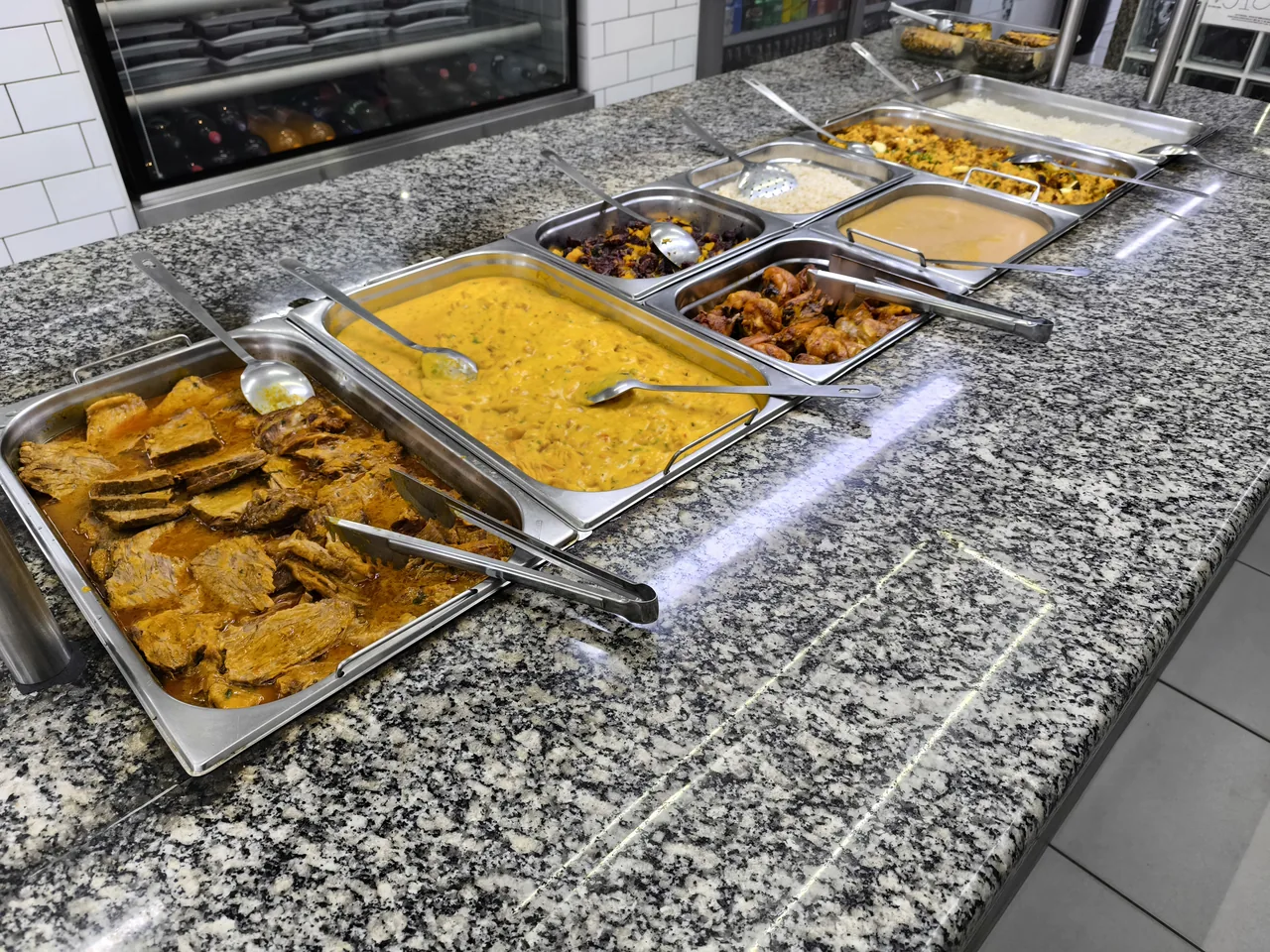 Bandejas do buffet por quilo com carnes e acompanhamentos